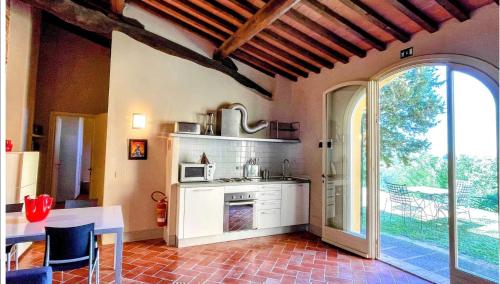 a kitchen with a table and a stove and a window at Incantevole borgo con piscine in Colleoli