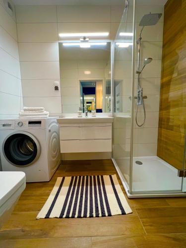 a bathroom with a washing machine and a shower at Apartament Nadmorski Hampton in Kołobrzeg