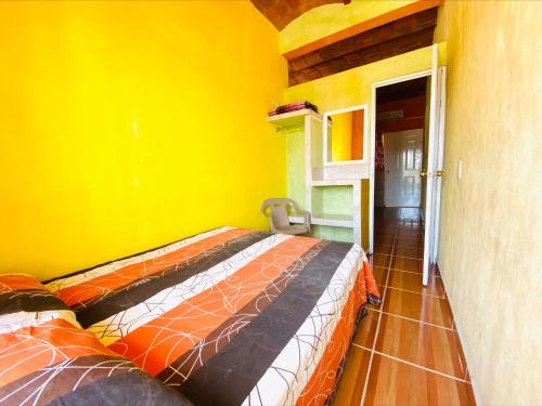 a bed in a room with a yellow wall at Bungalows El Rincon de La Riviera in Rincon de Guayabitos