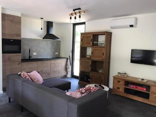 a living room with a gray couch and a tv at Vakantiewoning De Kleine Duinberg - Chalet Nr 9 in Retie