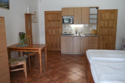 a room with a kitchen and a table and a bed at Penzion U Skutilů in Pilníkov