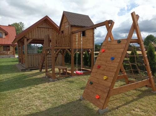 a playground with a wooden play house and a ladder at Przytulisko na Mazurach in Ruciane-Nida