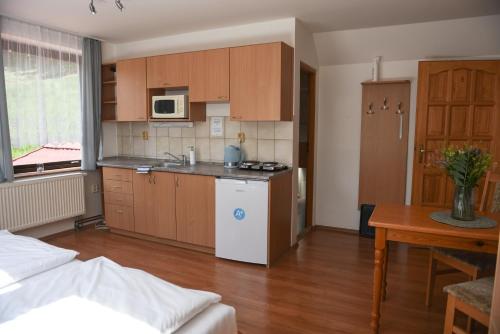 a kitchen with wooden cabinets and a white refrigerator at Penzion U Skutilů in Pilníkov