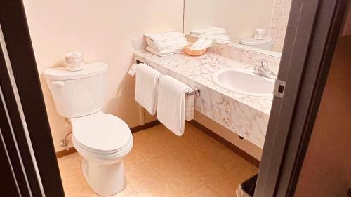 a bathroom with a toilet and a sink with towels at Airport Inn in Port Hardy