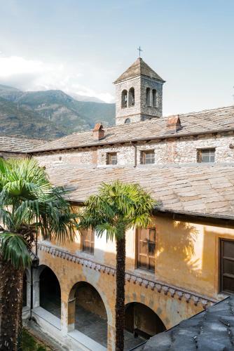 an old building with a clock tower and palm trees at Convento Boutique Hotel in Susa