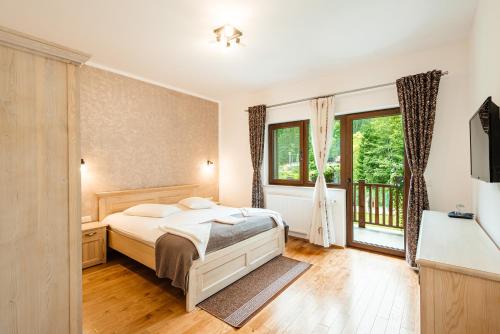 a bedroom with a bed and a large window at Pensiunea Agroturistică Casa Maria in Rodna