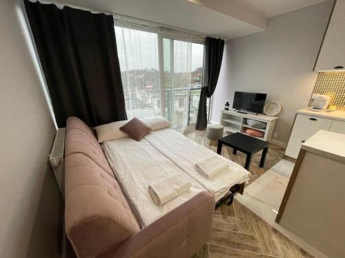 - une chambre avec un grand lit et une grande fenêtre dans l'établissement HIGH STANDARD APARTMENT GDYNIA, à Gdynia