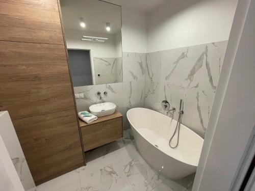 La salle de bains blanche est pourvue d'une baignoire et d'un lavabo. dans l'établissement HIGH STANDARD APARTMENT GDYNIA, à Gdynia