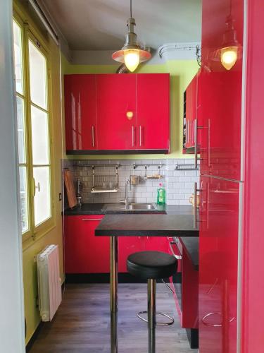 une cuisine avec des placards rouges et un comptoir noir dans l'établissement Home Sweet Home La Chapelle, à Paris