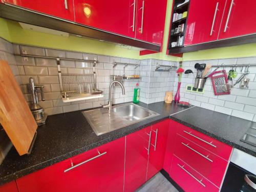 La cuisine est équipée de placards rouges et d'un évier en acier inoxydable. dans l'établissement Home Sweet Home La Chapelle, à Paris