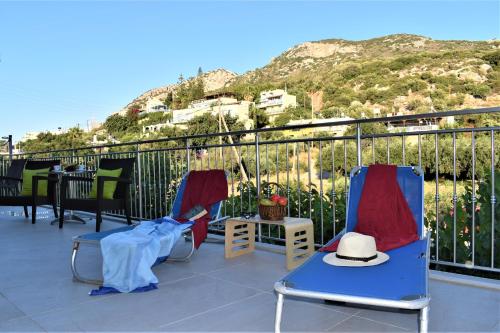twee stoelen en een hoed op een balkon met een berg bij Istron Corner Apartments in Istron