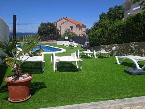 un patio con sillas blancas y una piscina en Villa Marin, en Pag