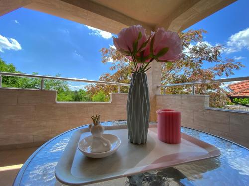 wazon z różowymi kwiatami na stole w obiekcie Vila Suncani Breg w mieście Veliko Gradište