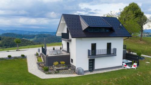 a small white house with a solar roof at Tanja s Holiday Home in Nature with sauna and hot tub in Gorica pri Slivnici