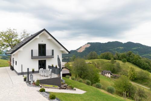 a white house on a hill with mountains in the background at Tanja s Holiday Home in Nature with sauna and hot tub in Gorica pri Slivnici