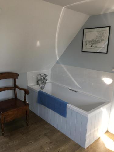 a bathtub in the corner of a room with a chair at Barn Flat overlooking beautiful Dorset vale in Sherborne