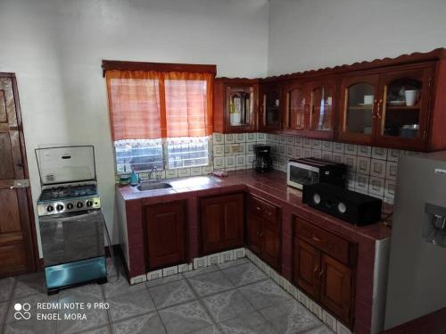 a kitchen with wooden cabinets and a stove top oven at Casa y Hospedaje Norma in Moyogalpa
