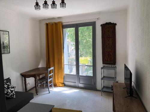 a living room with a table and a sliding glass door at Appartement de charme Avignon CENTRE HISTORIQUE TERRASSE et BALCON Place PIE in Avignon