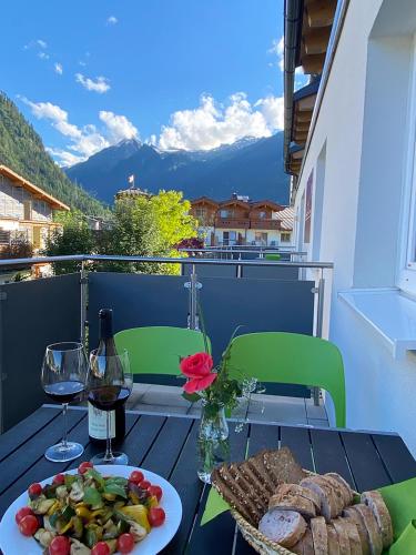 a table with a plate of food and a glass of wine at Art Apart Nomay Summercard Blick Top of Salzburg in Kaprun