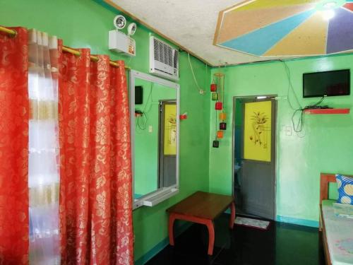a room with green walls and orange curtains at Glenmark's Homestay 2 in Mabubua