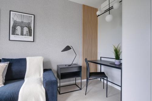 a bedroom with a blue bed and a desk with a lamp at Modern Studio Targowa 10 AC in Warsaw