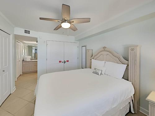 1 dormitorio con cama blanca y ventilador de techo en Regency Towers 802 East, en Pensacola Beach