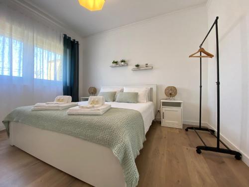 una camera da letto bianca con un letto con due asciugamani sopra di Casa Margarida ad Apúlia
