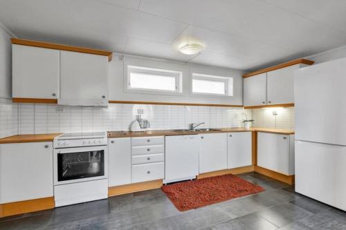 a kitchen with white cabinets and white appliances at Romslig og fin leilighet 17 min til Kristiansand Centrum in Nodeland