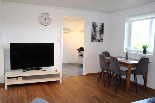 a living room with a television and a table with chairs at Romslig og fin leilighet 17 min til Kristiansand Centrum in Nodeland
