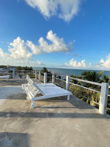 a white bench sitting on a pier overlooking the ocean at Caye Caulker Beach Hotel in Caye Caulker