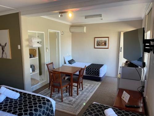 a small room with a table and a bed and a bedroom at Quirindi Sunflower Motor Inn in Quirindi