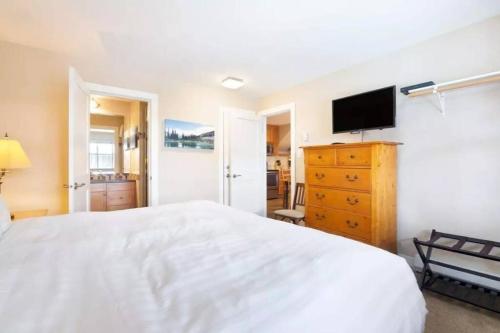 a bedroom with a white bed and a tv at Ski-in Ski-out at upper village next to Fairmount Hotel In Whistler in Whistler