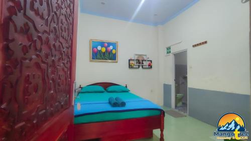a bedroom with a bed and a painting on the wall at Mango Tree Homestay & Ijen Tour in Banyuwangi
