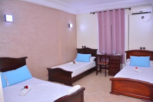 una camera d'albergo con 2 letti e una scrivania di Hôtel Elfekri a Er Rachidia