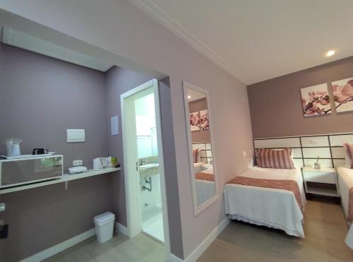 a small room with a bed and a mirror at Hospedagem Jardins de Gramado in Gramado