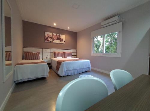 a room with two beds and a window at Hospedagem Jardins de Gramado in Gramado