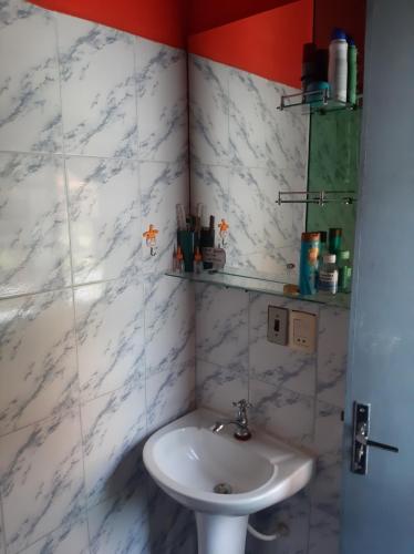 baño con lavabo y paredes de mármol blanco en Hospedaje Margarita, en Encarnación