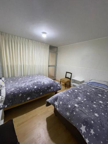 a bedroom with two beds and a chair at Casa 1er piso D&C in Huancayo