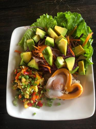 a white plate with a salad with lettuce and vegetables at On The Mekong Resort in Luang Prabang