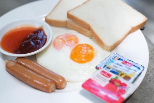 a plate of food with eggs sausage bread and toast at Muntra Garden Resort in Sattahip