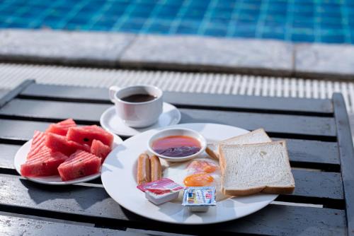 a plate of food with bread and a cup of coffee at Muntra Garden Resort in Sattahip