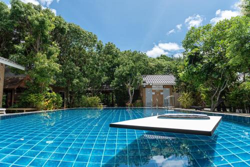 a swimming pool in a resort with trees in the background at Muntra Garden Resort in Sattahip