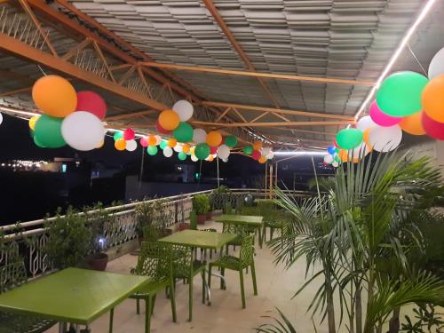 a restaurant with green tables and colorful balloons hanging from the ceiling at Hotel Temple On Ganges in Varanasi