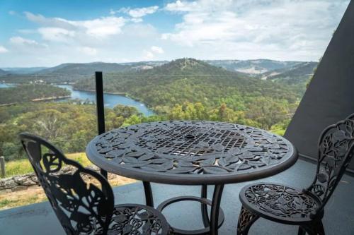 a table and chairs on a balcony with a view of a river at Eagle View Escape in Rydal