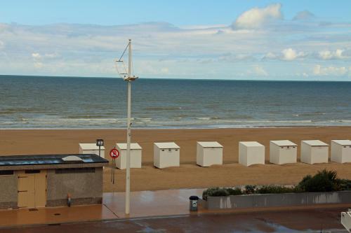 a beach with a row of white chairs and the ocean at Duinroos C2 in Koksijde