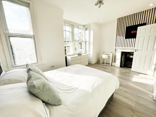 a white bedroom with a large bed and a fireplace at Minet Gardens House - Suite 6 in London