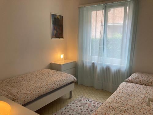 a small bedroom with two beds and a window at Appartamento con giardino al Melograno in Locarno