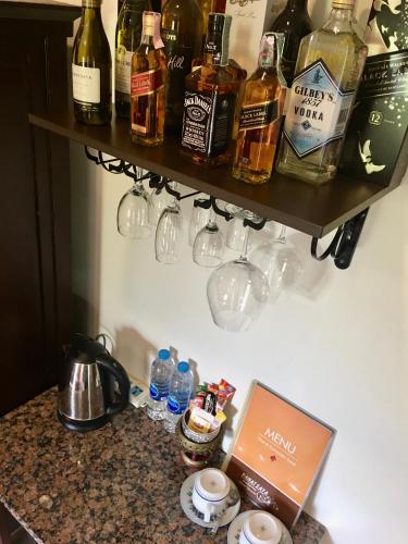 a shelf with bottles and glasses on a wall at Naraya Homestay in San Pa Tong