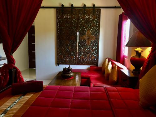 a living room with a red couch and a table at Naraya Homestay in San Pa Tong