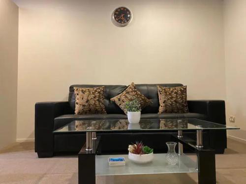 a black couch with a glass table in a living room at 2 Bedroom house in Hamilton Central in Hamilton
